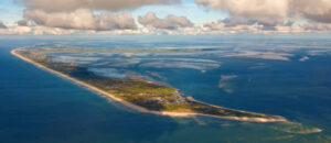 Aerial view of Sylt, surrounded by ocean, on a partially cloudy day.