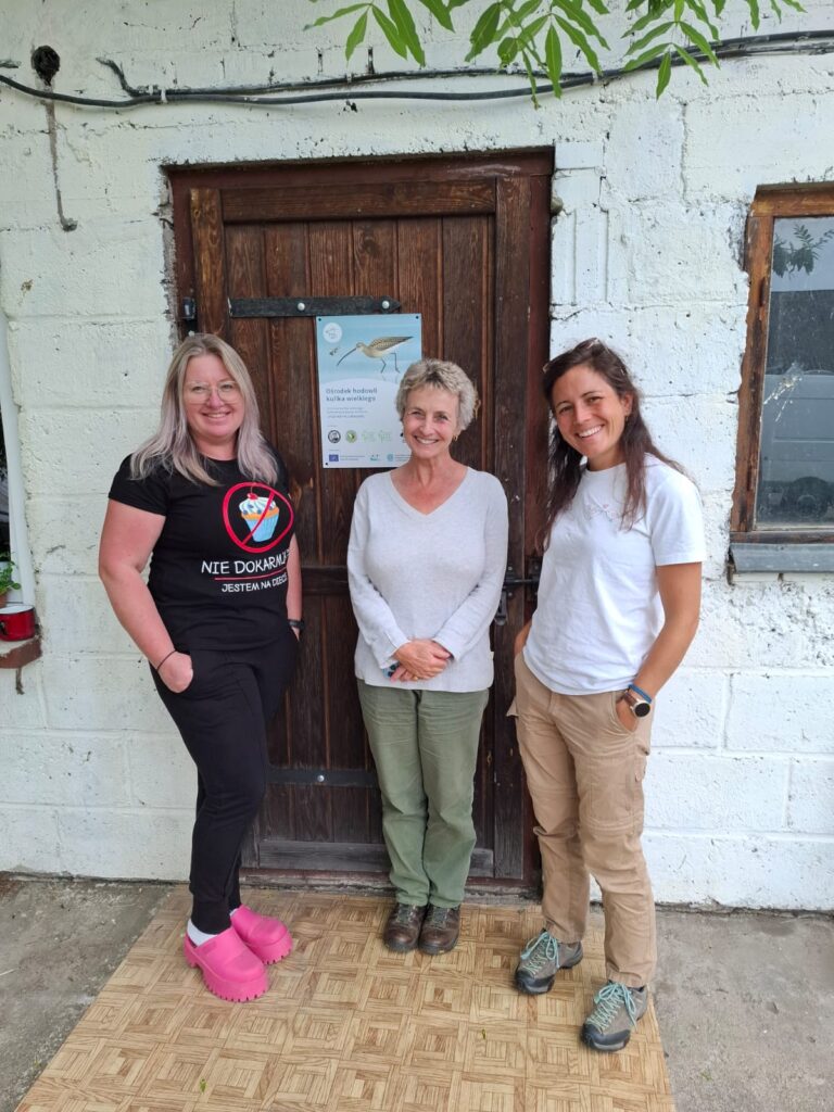 Three women standing outside a building and smiling at the camera.