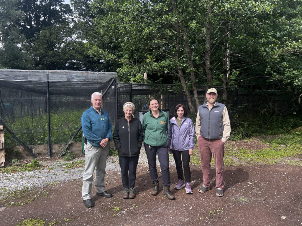 A photo of five people standing together and smiling at the camera.