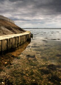 A photo of a seawall with a cloudy sky above.