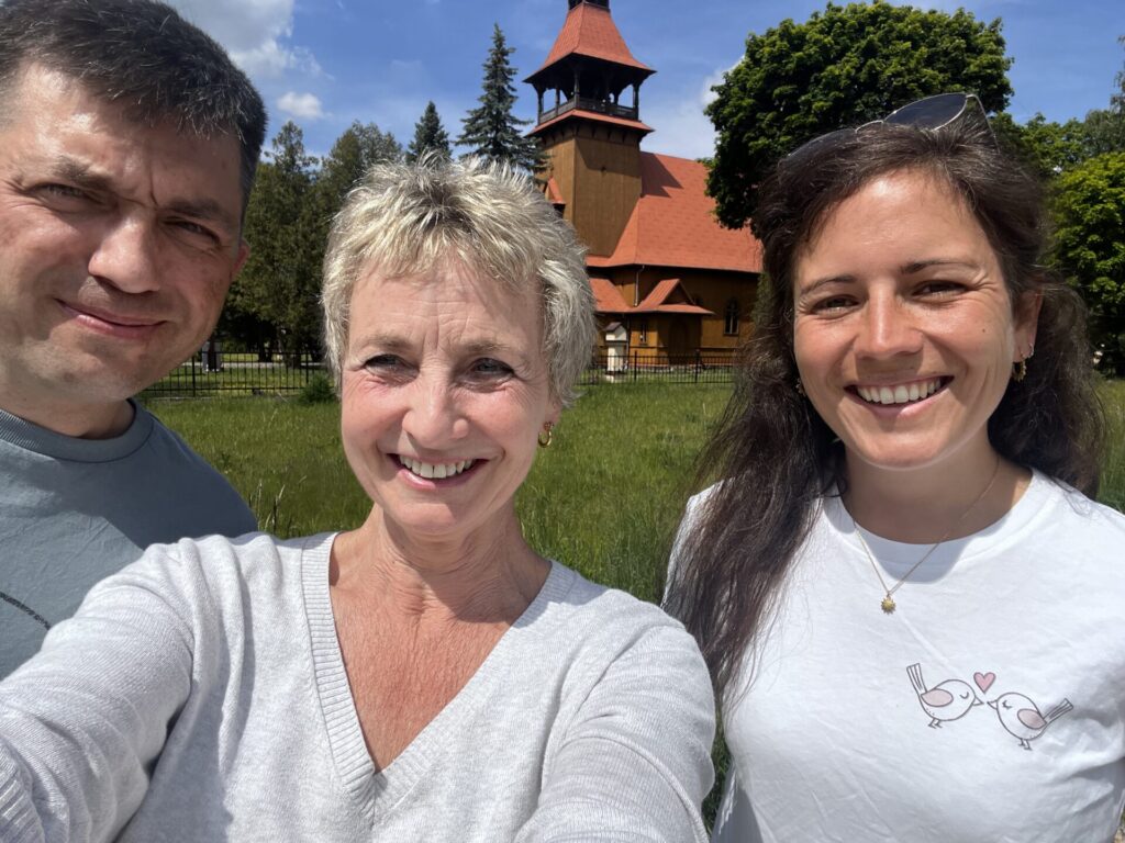 A selfie photo of three people smiling at the camera, in the sunshine.