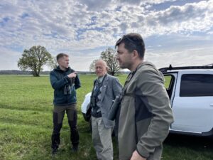 A photo of three men standing by a car 