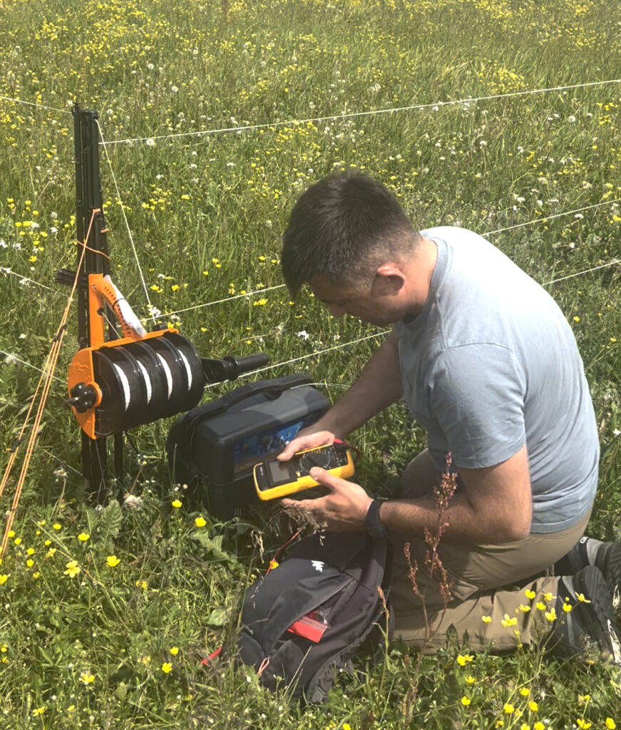 A man checking an electric fence.